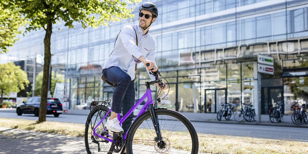 Mann mit Sonnenbrille fährt Fahrrad in der Stadt bei sonnigen Wetter